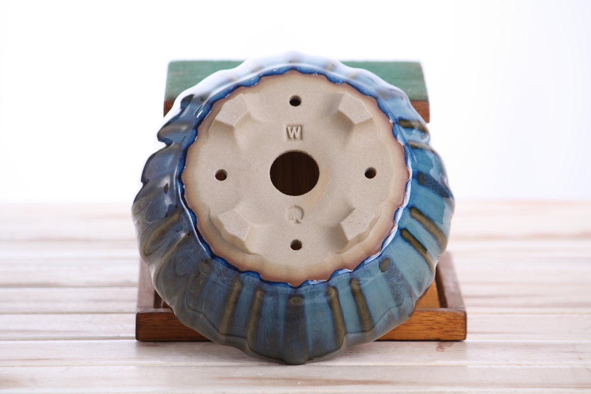 Underside of the blue-green round fluted bonsai pot showing drainage openings, feet and impressed maker's marks