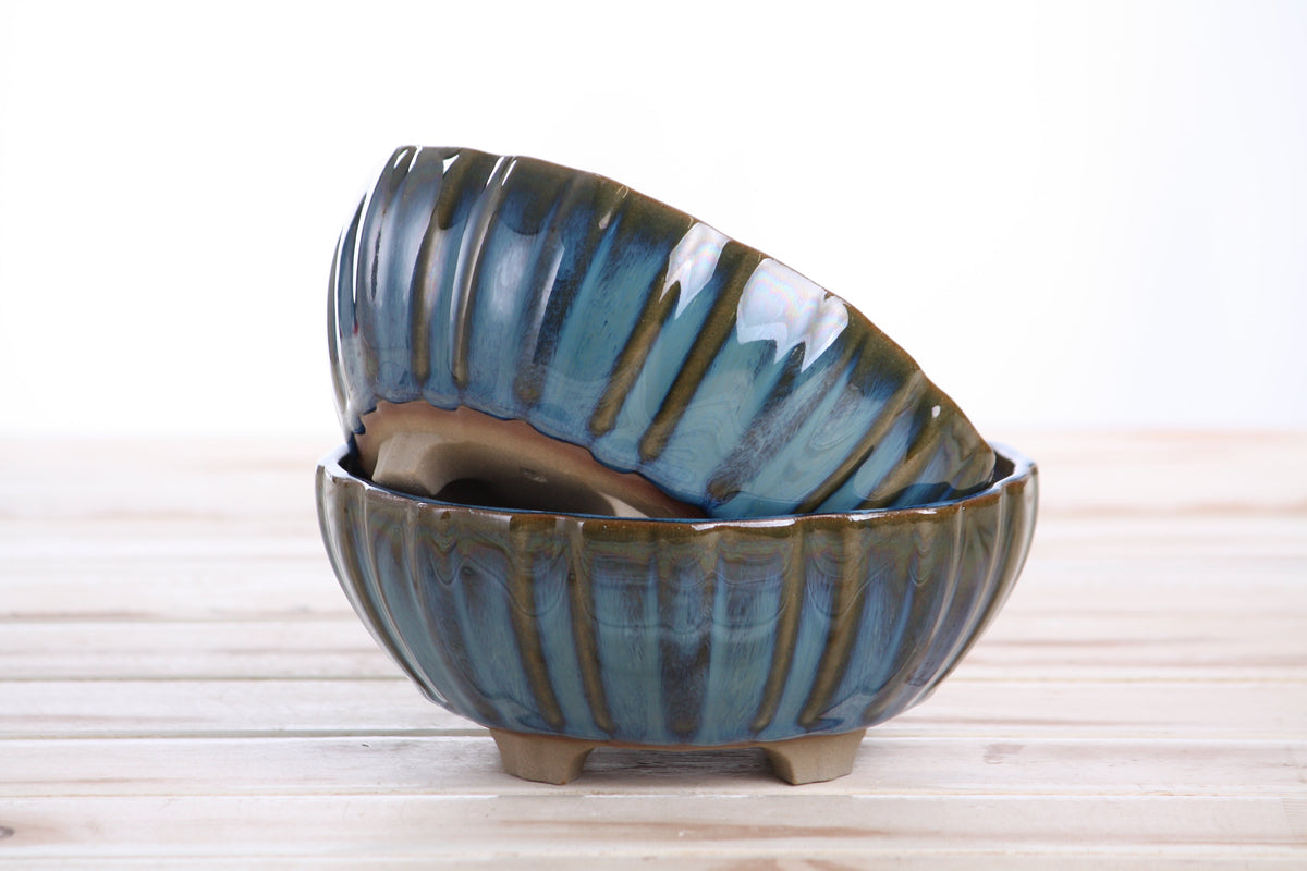 Two matching blue-green pots stacked at an angle to show their profiles