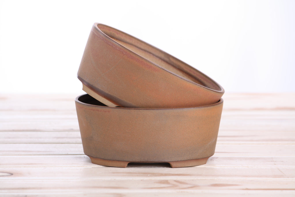Two matching tan-brown pots stacked at an angle to show their profiles