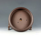 Interior of the brown round pot showing central drainage and smaller holes