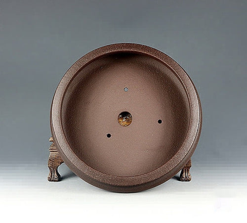 Interior of the brown round pot showing central drainage and smaller holes