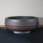 Rounded body and raised feet of dark-brown bonsai pot