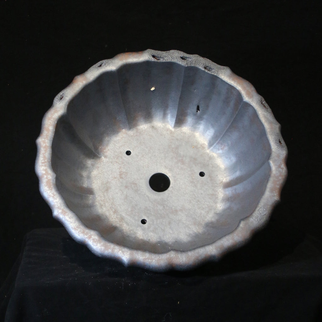 Top view of dark lotus-shaped bonsai pot showing fluted interior, central opening and smaller holes