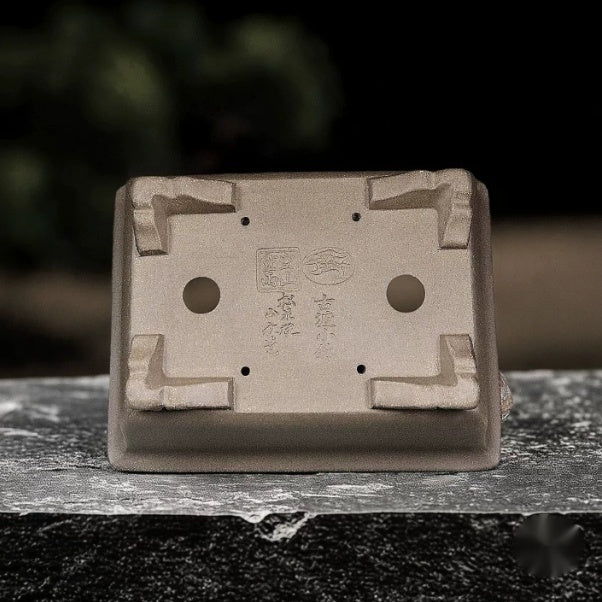 Underside of taupe rectangular pot showing openings, corner feet and stamped marks