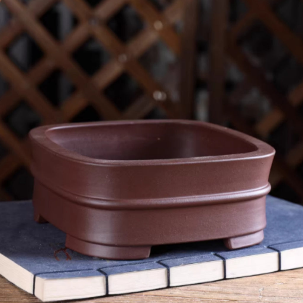 Brown rounded square bonsai pot with raised central band and block feet