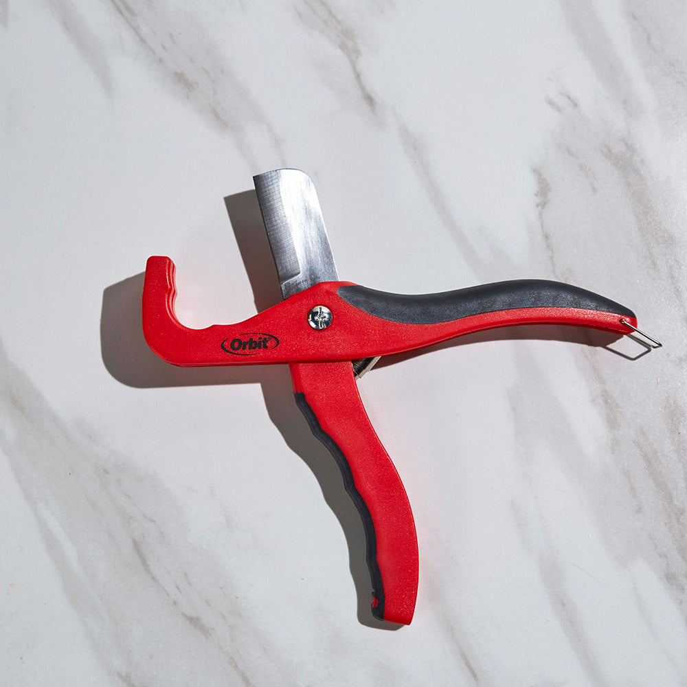 Close-up of the red and black Orbit tubing cutter with its blade exposed