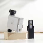 Gray B-hyve hose timer beside a black plug-in hub on a wooden block