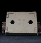 Underside of the taupe pot showing corner feet, drainage holes and impressed marks