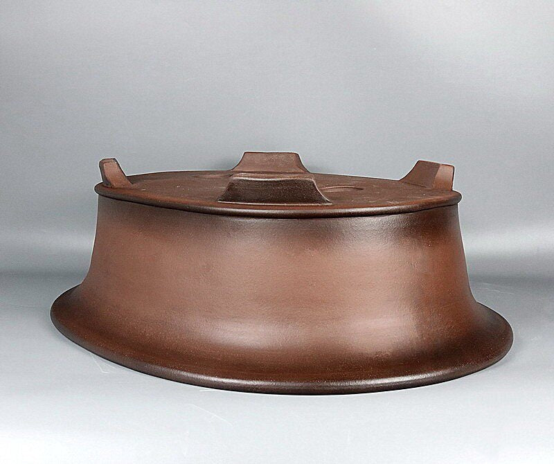 Upside-down brown oval pot showing raised feet and tapered wall