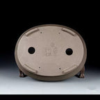 Underside of the taupe oval pot with seals and drainage openings