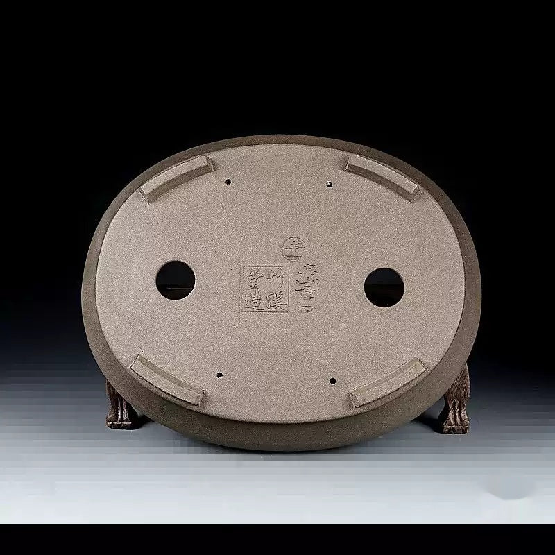 Underside of the taupe oval pot with seals and drainage openings