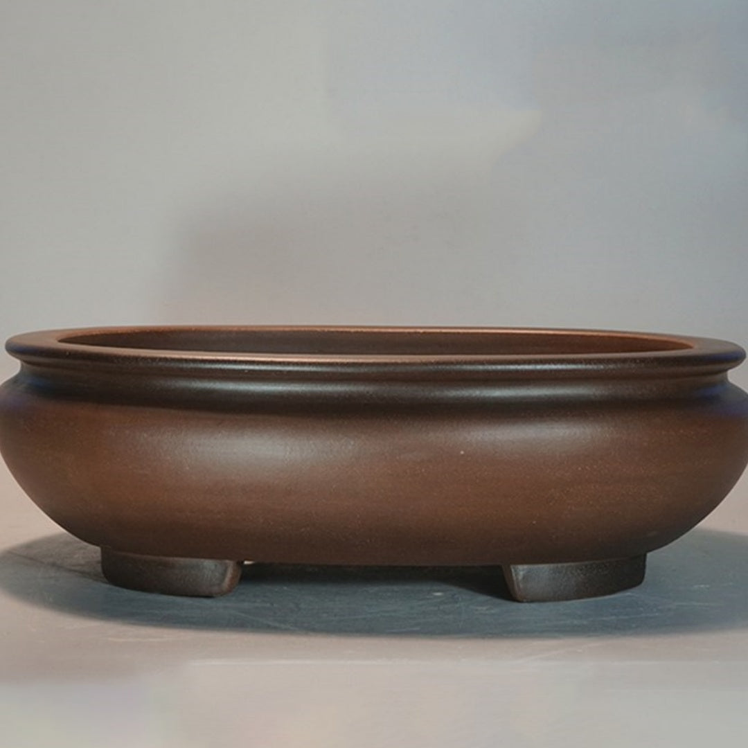 Front view of the brown oval pot showing its rolled rim and short feet