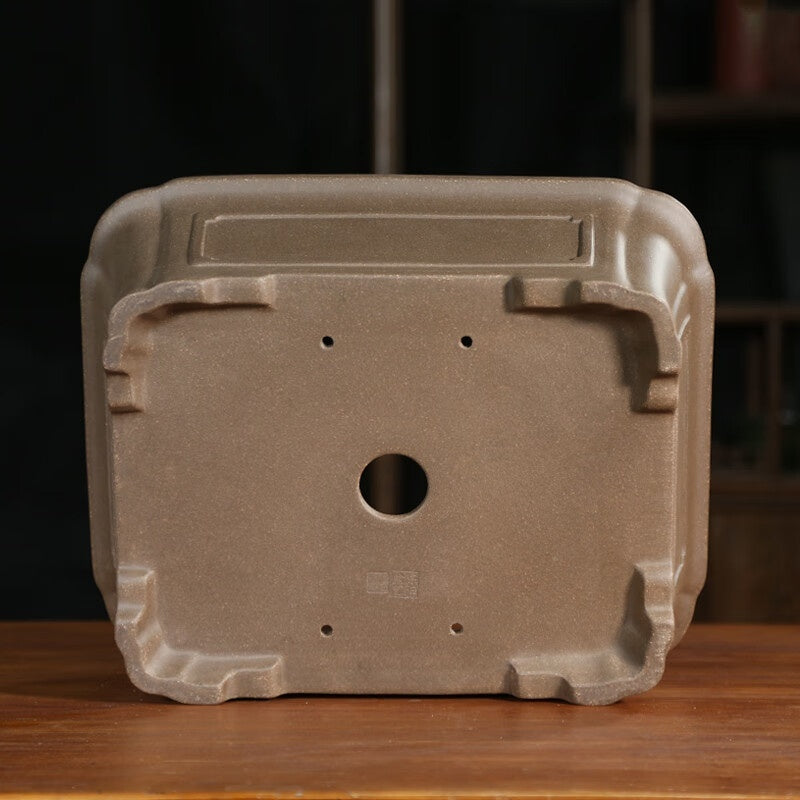 Base of the tan rectangular pot showing one drainage hole and four smaller openings