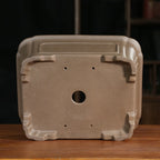Base of the tan rectangular pot showing one drainage hole and four smaller openings