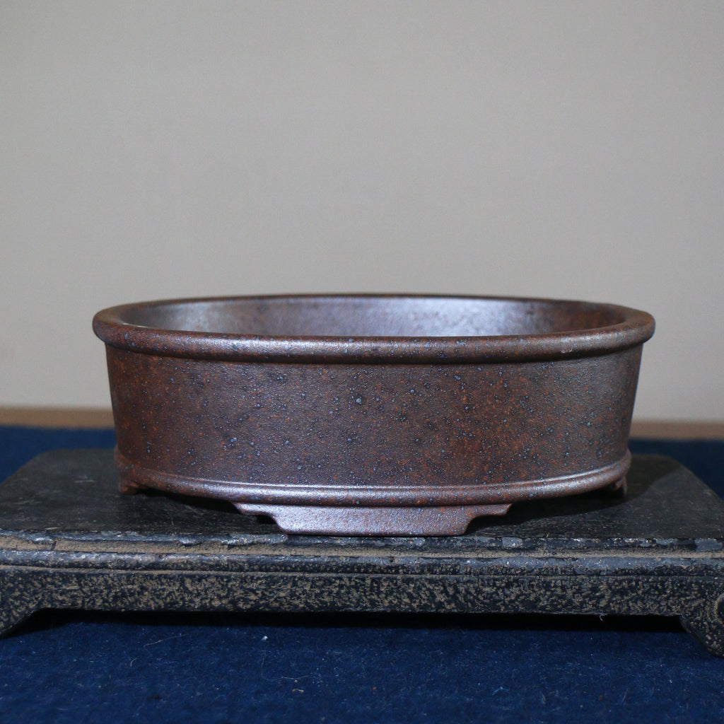 Front profile of mottled brown oval pot on a stone stand