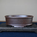 Front profile of mottled brown oval pot on a stone stand