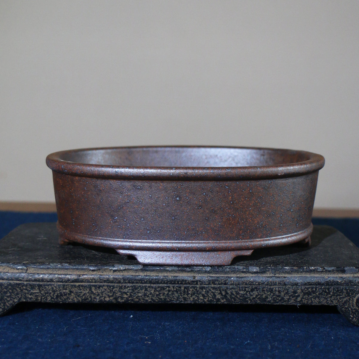 Front profile of mottled brown oval pot on a stone stand
