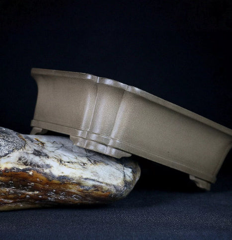 Side profile of taupe rounded rectangular pot tilted on stone