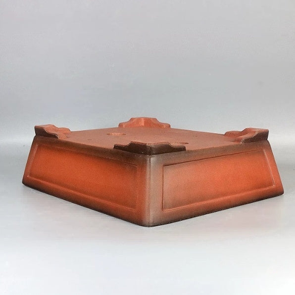 Angled underside of orange-brown rectangular pot showing corner feet