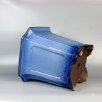 Blue-glazed tall square bonsai pot lying on its side showing paneled wall