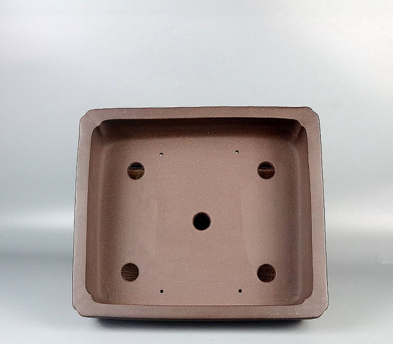 Interior of the brown rectangular pot showing five large drainage openings