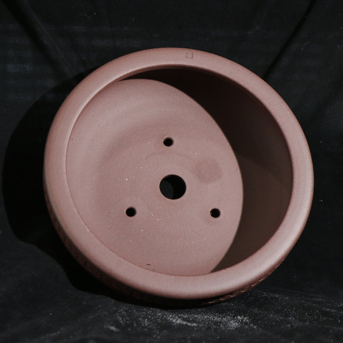 Interior of the reddish-brown round pot with central drainage hole