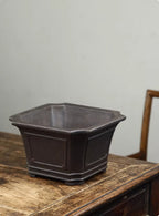 Angled view of dark square pot showing open interior and paneled sides
