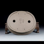 Underside of taupe oval pot showing openings, feet and stamped marks