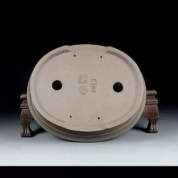 Underside of taupe oval pot showing openings, feet and stamped marks