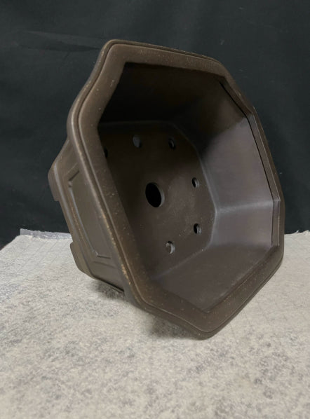 Dark brown clipped-corner pot tipped upright to show interior openings