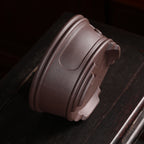 Brown round pot tipped on its side to show banded wall and feet