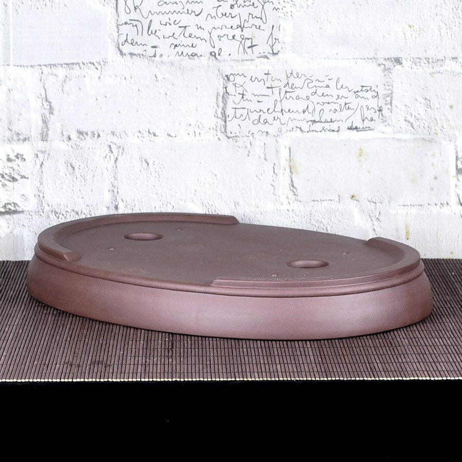 Upside-down brown oval bonsai pot showing low feet and base openings