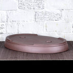 Upside-down brown oval bonsai pot showing low feet and base openings