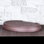 Upside-down brown oval bonsai pot showing low feet and base openings