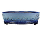 Angled view of the blue studded drum pot with low feet