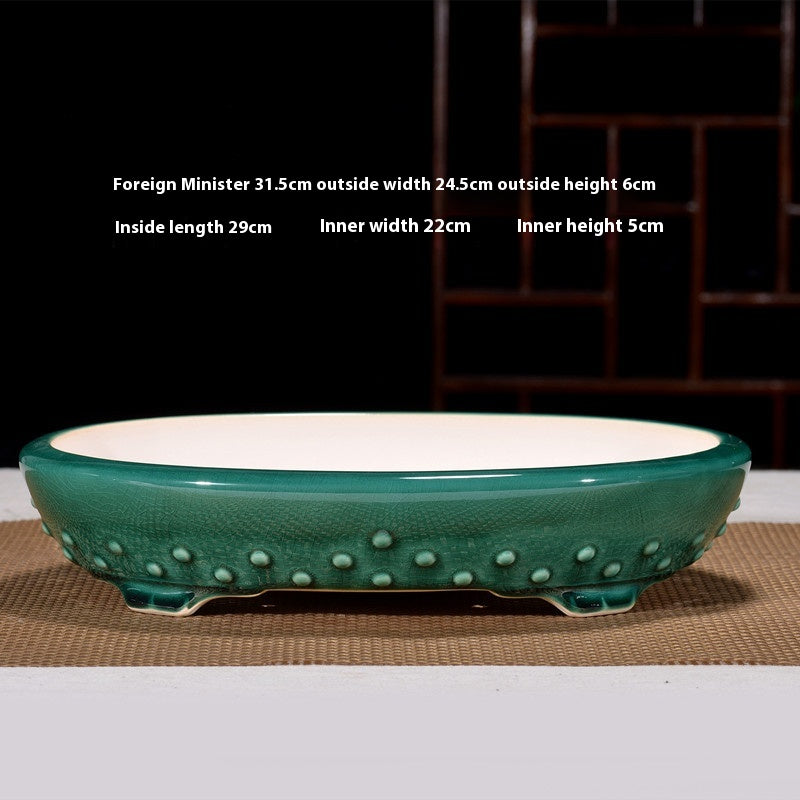 Green oval bonsai pot with raised studs around the base and pale interior, with dimensions above