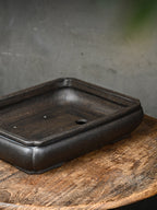 Angled interior view of the dark rectangular pot with a visible drainage opening