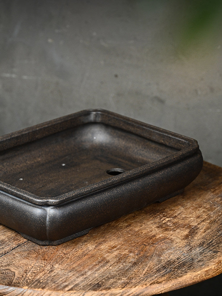 Angled interior view of the dark rectangular pot with a visible drainage opening