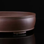 Close-up of brown oval pot showing double rim and low foot