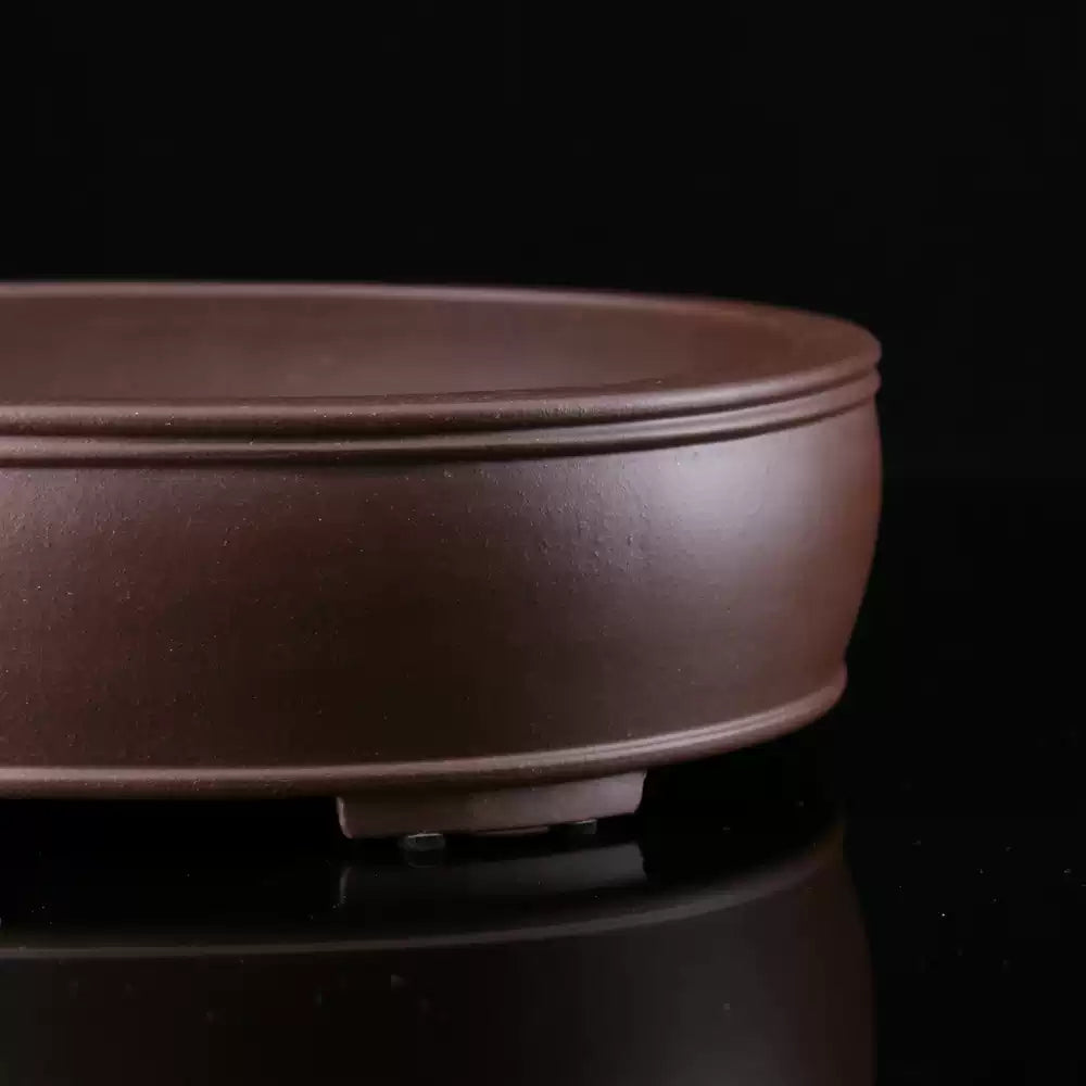 Close-up of brown oval pot showing double rim and low foot