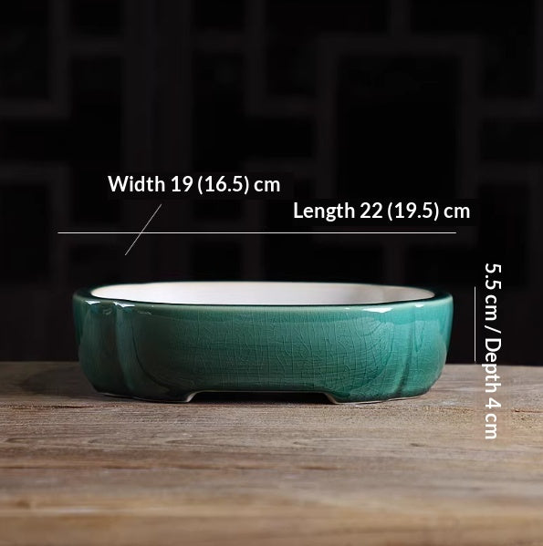 Deep green oval bonsai pot with a pale interior and low feet, with measurement labels