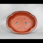 Top view of red-orange lobed pot showing two large openings and small holes