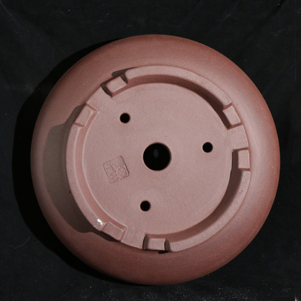 Underside of the round pot showing feet, seal and drainage openings
