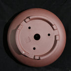 Underside of the round pot showing feet, seal and drainage openings