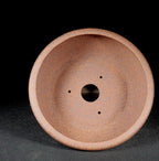 Interior of the brown round pot with central drainage hole and smaller openings
