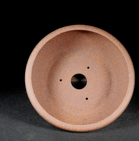 Interior of the brown round pot with central drainage hole and smaller openings