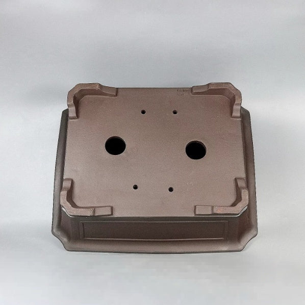 Underside of brown rectangular pot showing two large openings and four small holes