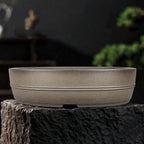 Taupe oval pot with two narrow horizontal bands and low feet