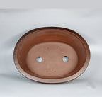 Top view of large brown oval pot showing two large openings and small holes