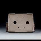 Underside of taupe rectangular pot showing two large openings and four small holes